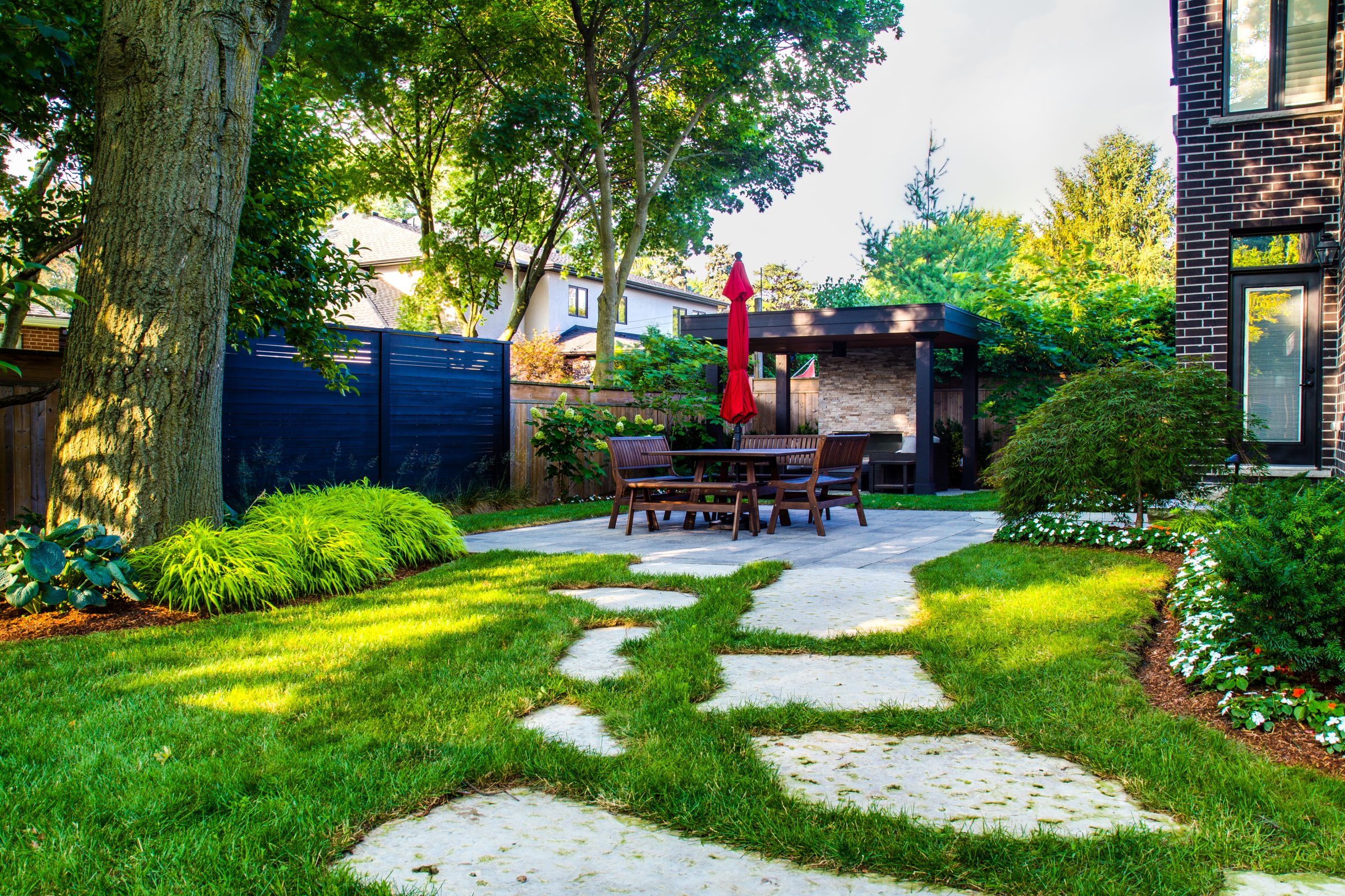 Backyard patio with table, chairs, and greenery.