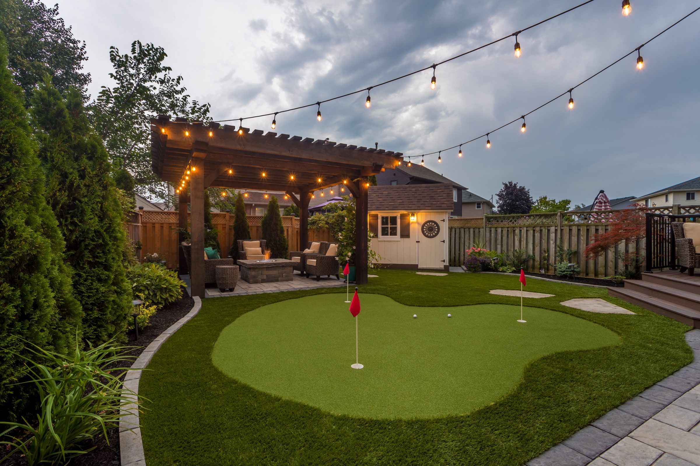 Backyard pergola with putting green and lights.