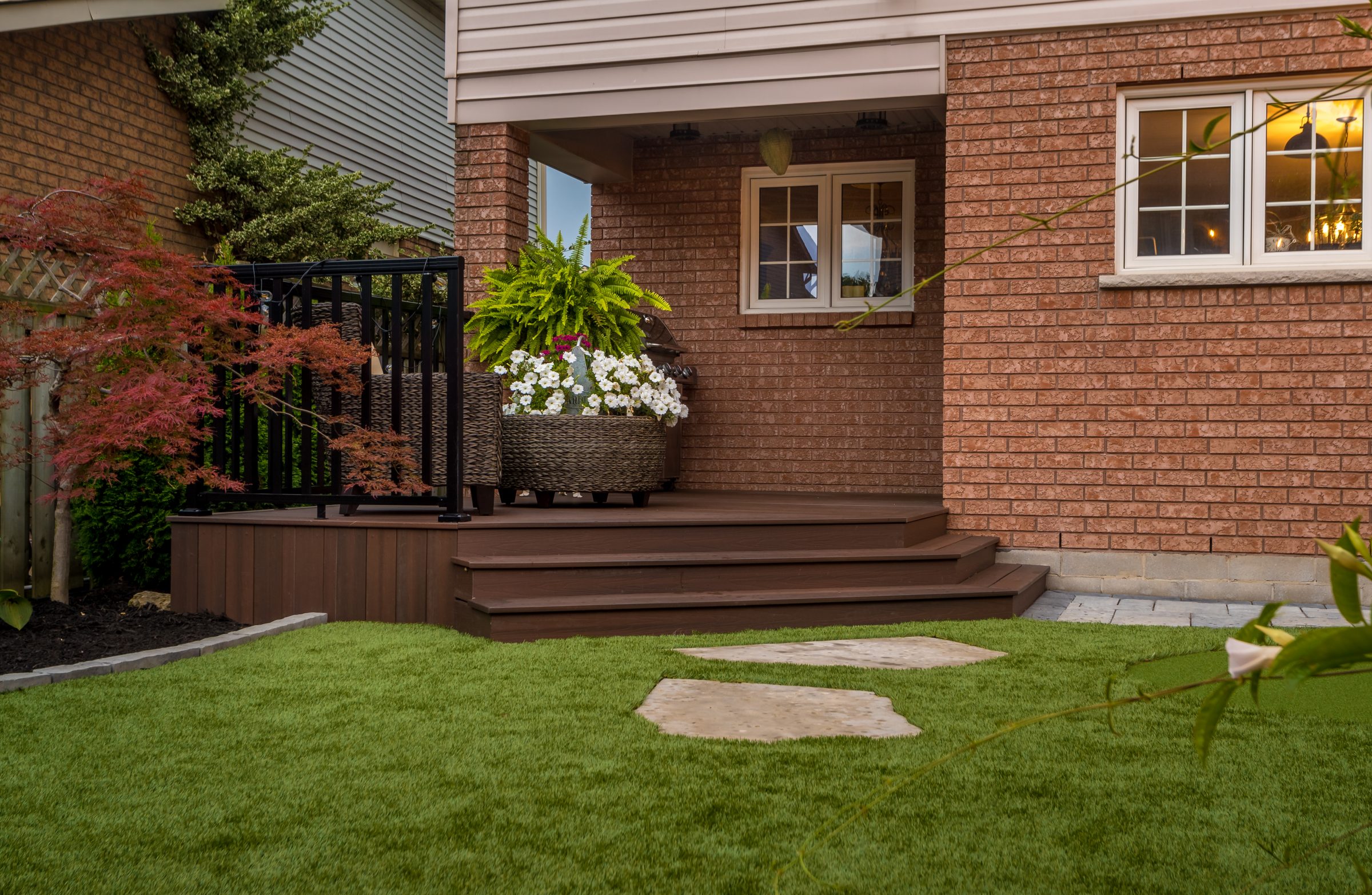 Backyard patio with plants and brick wall.