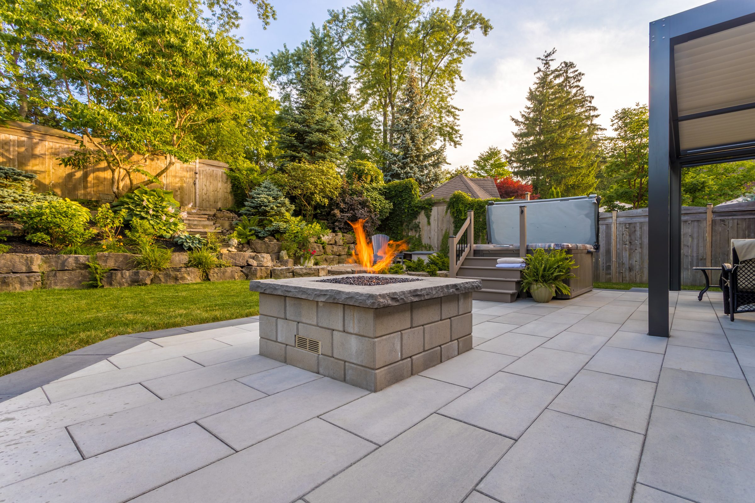 Backyard patio with fire pit and greenery.