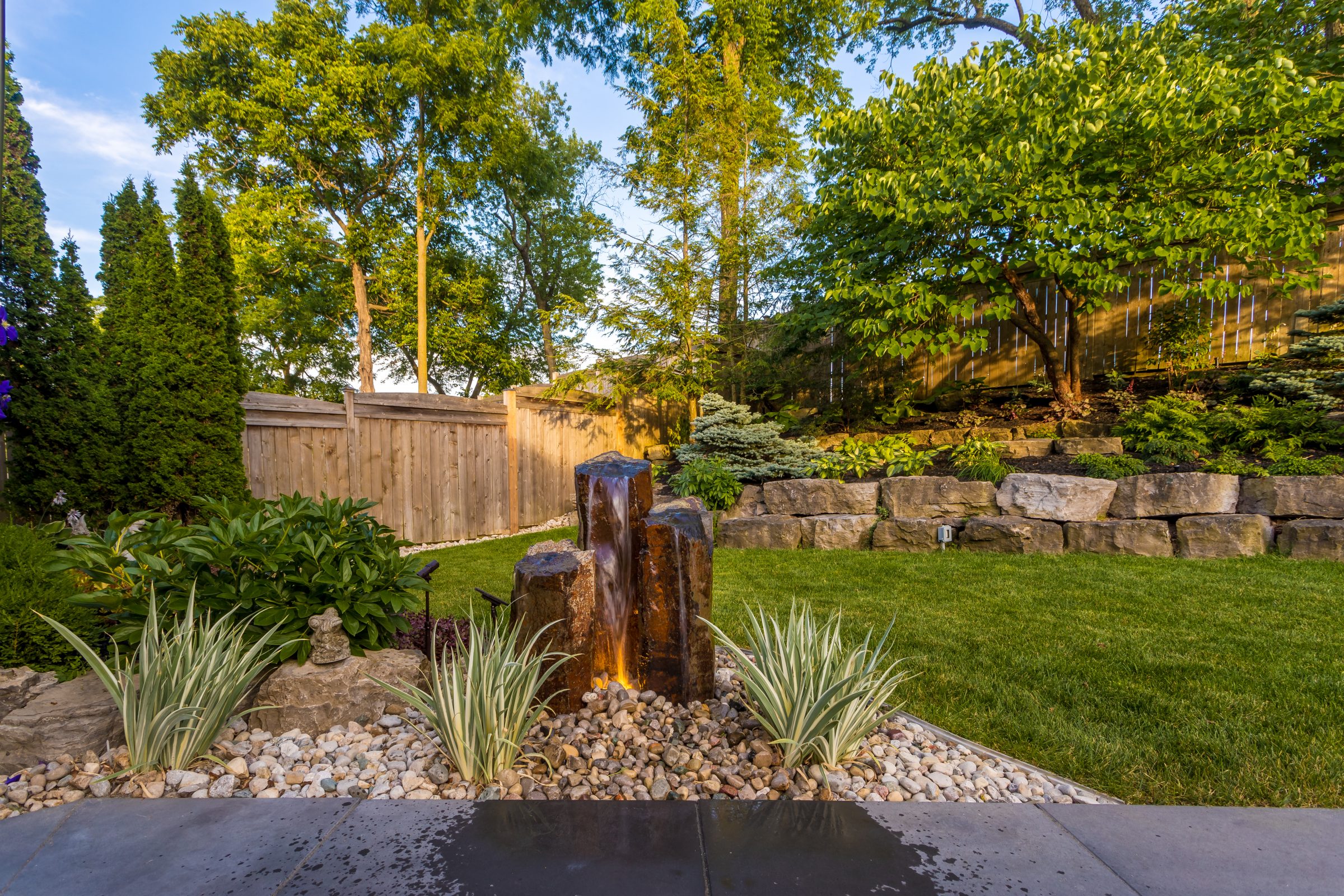 Backyard with stone waterfall and lush greenery