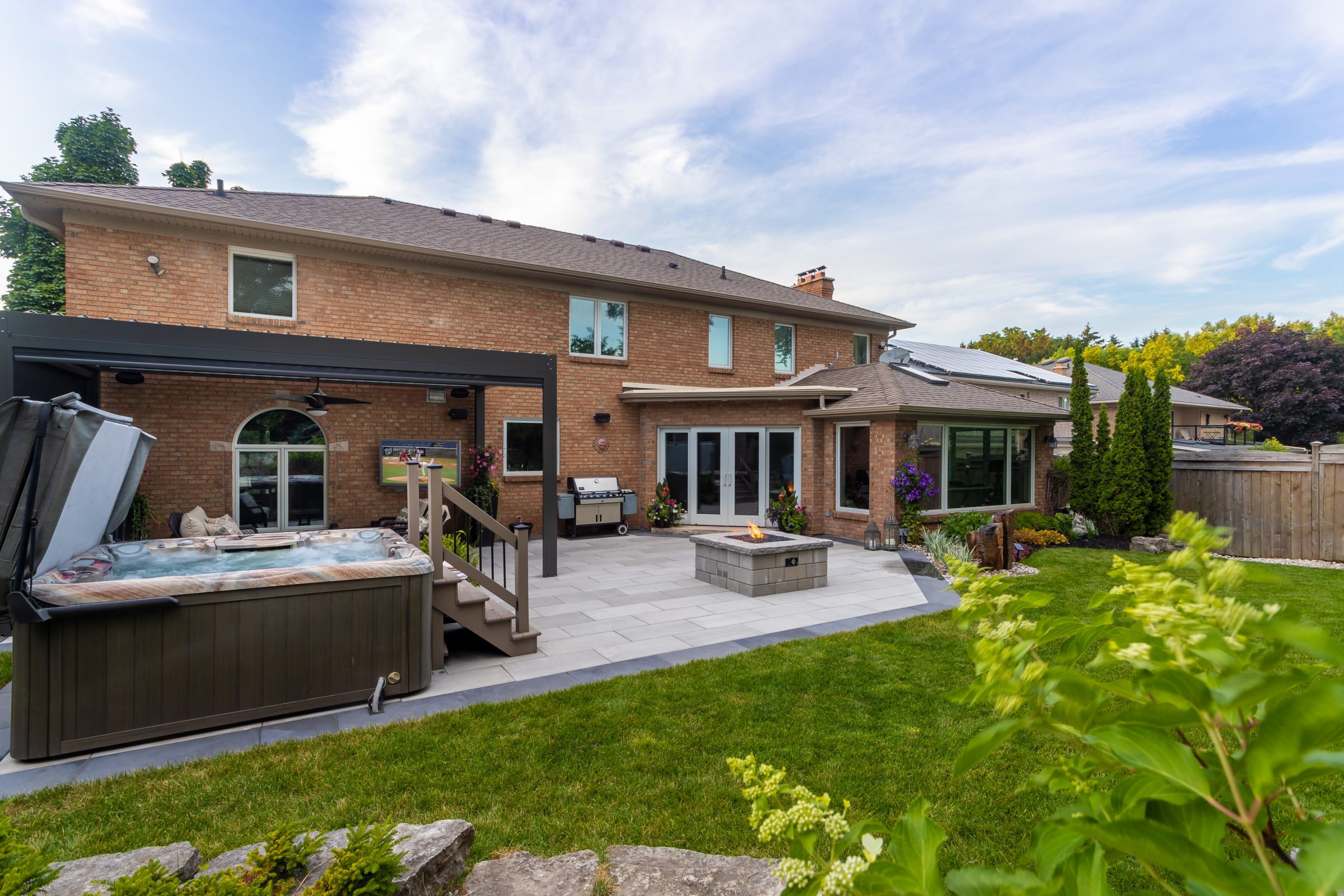 Brick house with patio and spa in backyard