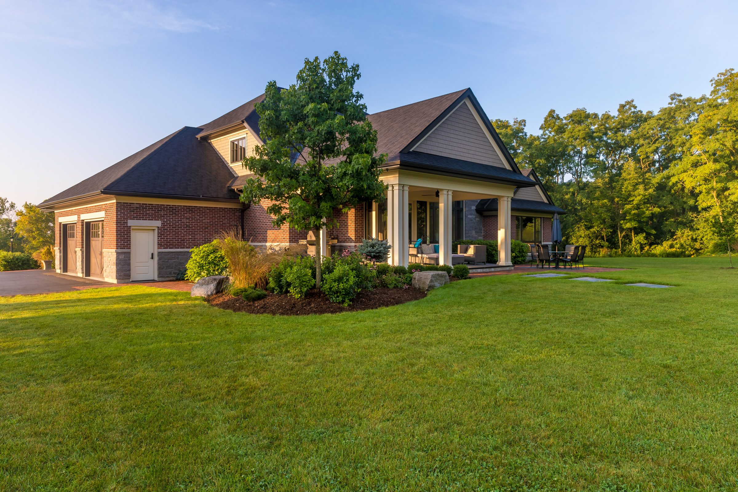 Spacious suburban house with green lawn and trees.
