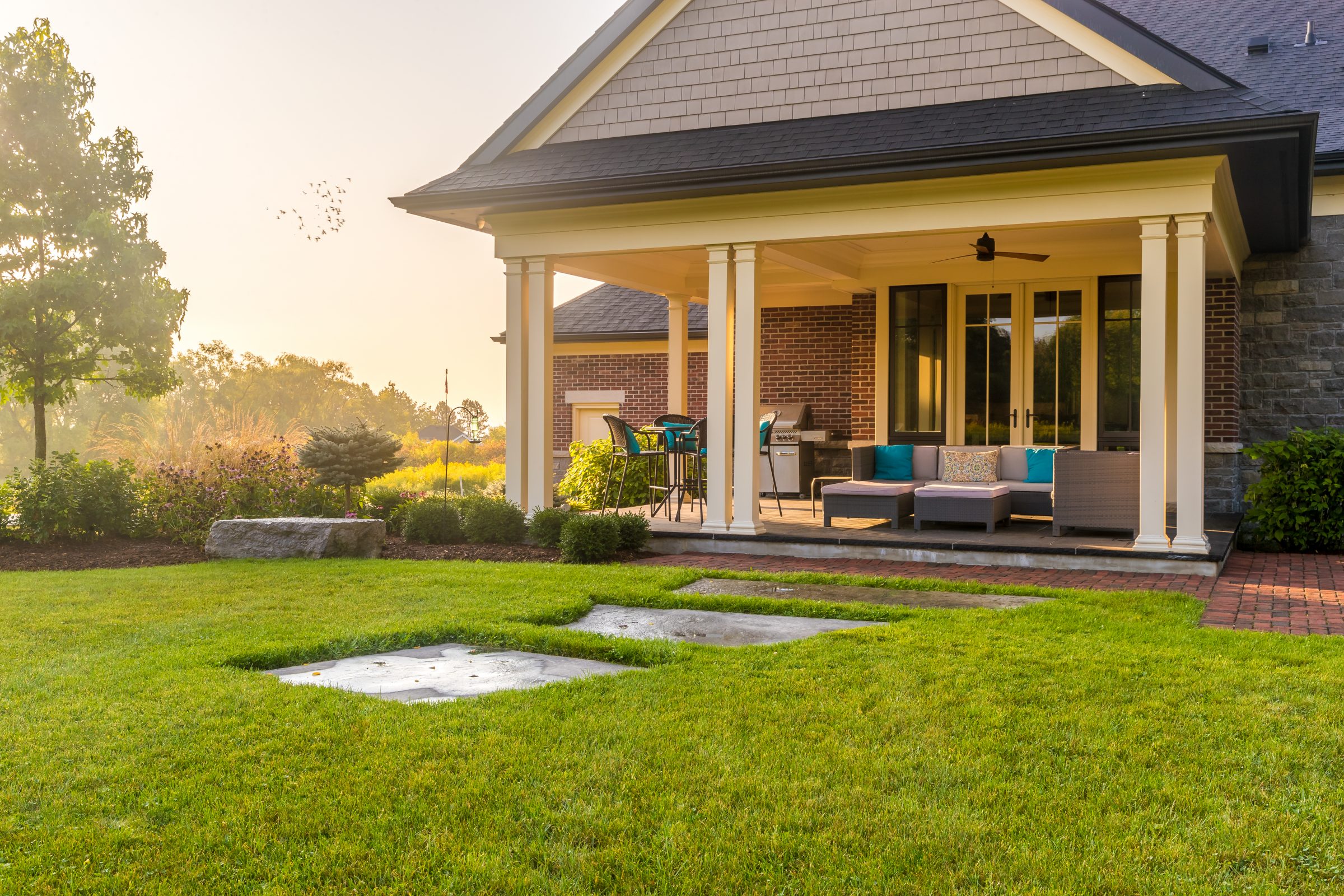 Cozy patio with furniture and lush green lawn.
