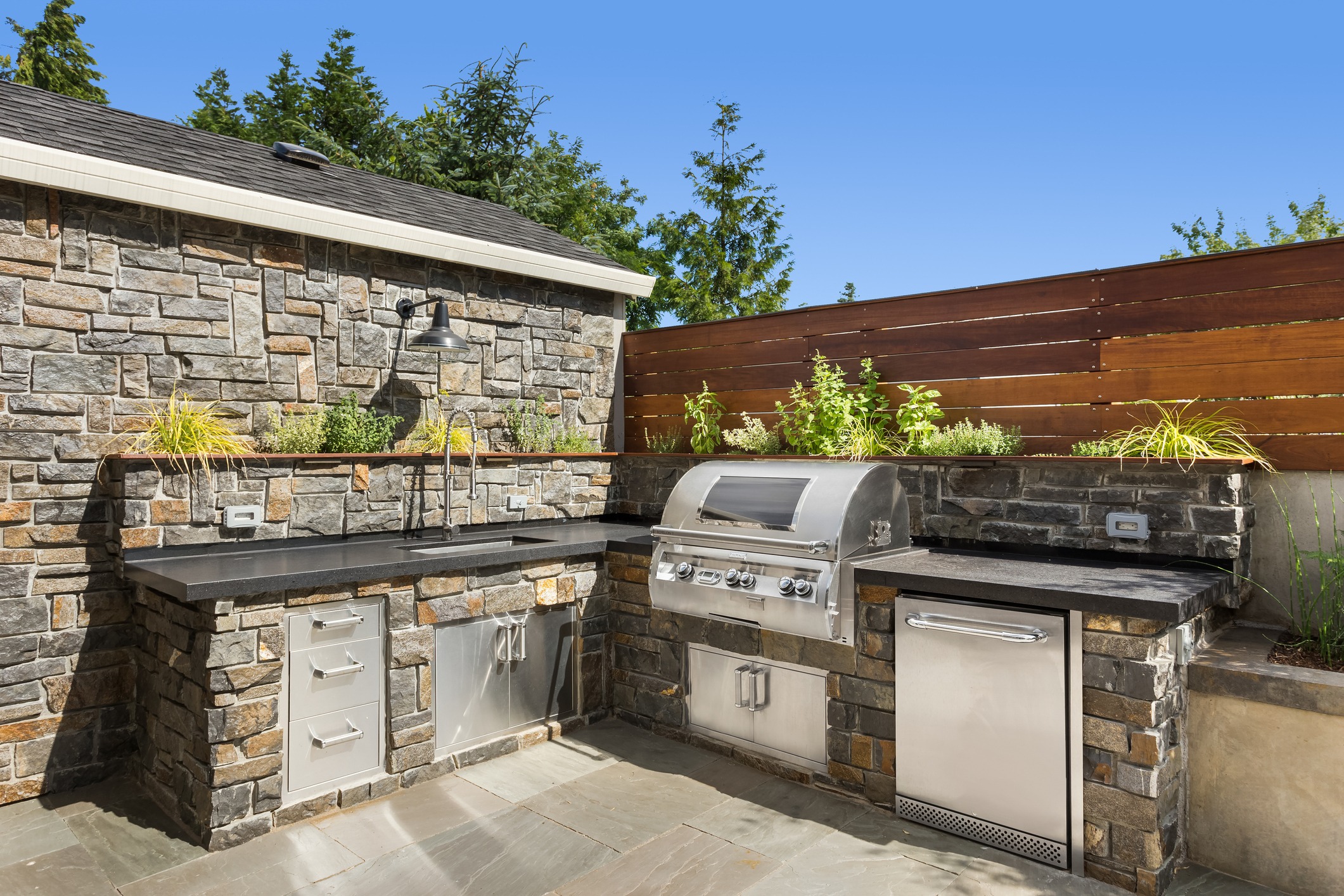 Modern outdoor kitchen with stone design and grill.