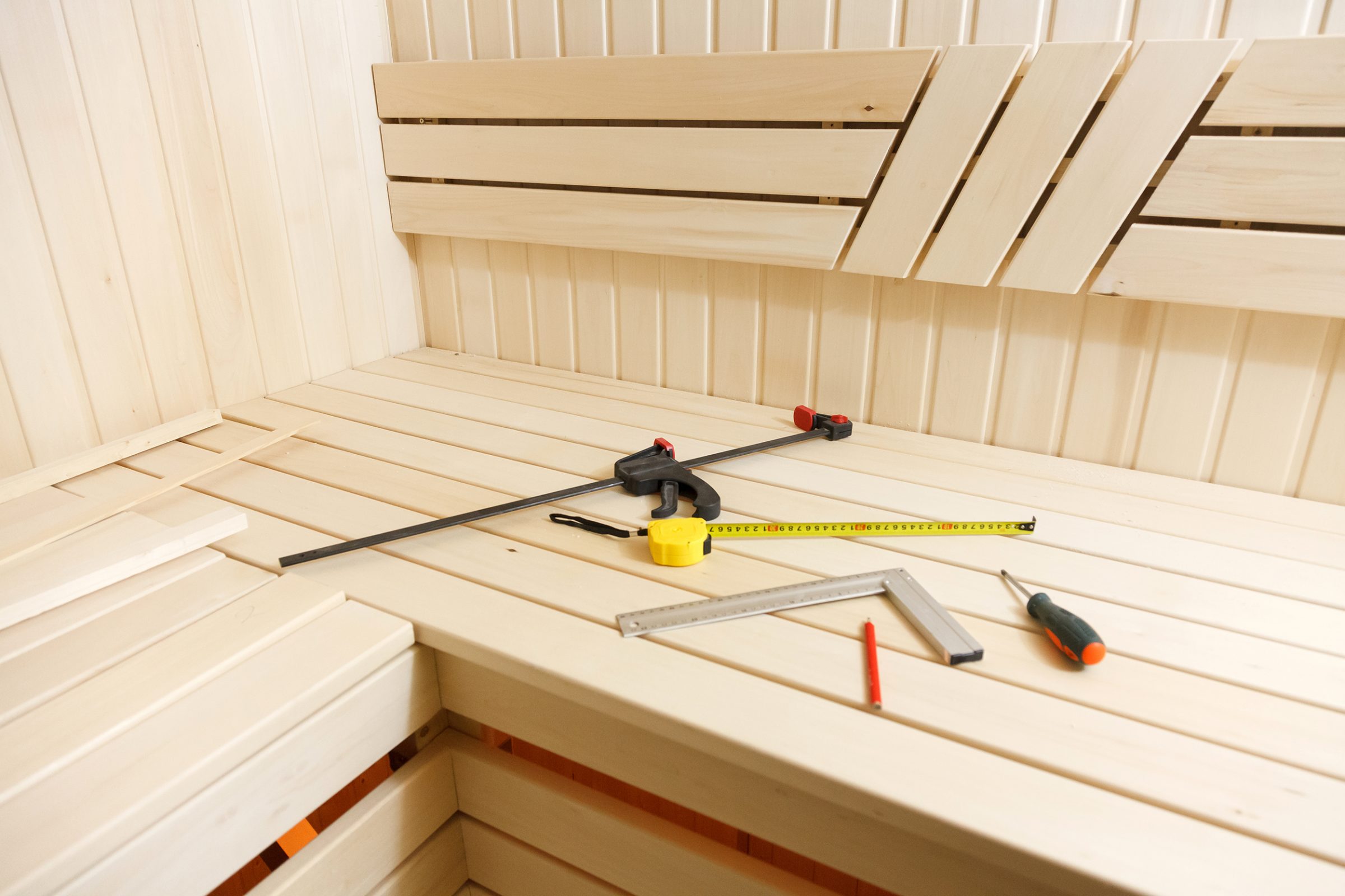 Wooden sauna bench with construction tools on it.