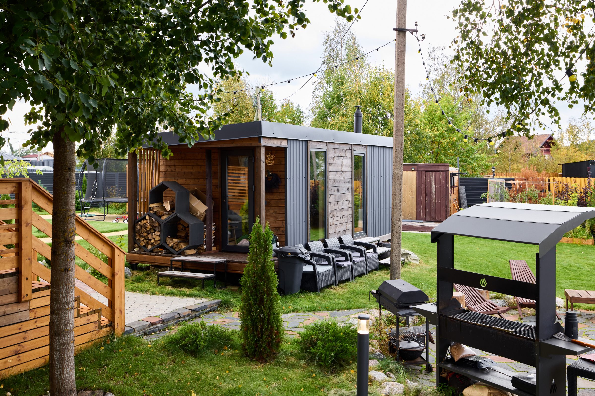 Modern backyard with sauna, chairs, and outdoor grill.